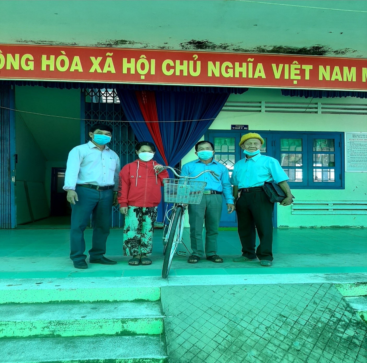 Ông Nguyễn Văn Anh Tông và ông Nguyễn Văn Mít(bên phải) Hội khuyến học xã Tân Thành B trao xe đạp cho em La Thị Kim Hồng, học sinh lớp 2 của trường.